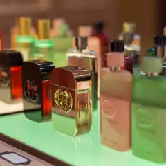 Gdzie kupić oryginalne testery perfum? Rząd luksusowych flakonów Gucci Guilty na zielonej półce.
