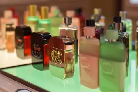 Gdzie kupić oryginalne testery perfum? Rząd luksusowych flakonów Gucci Guilty na zielonej półce.