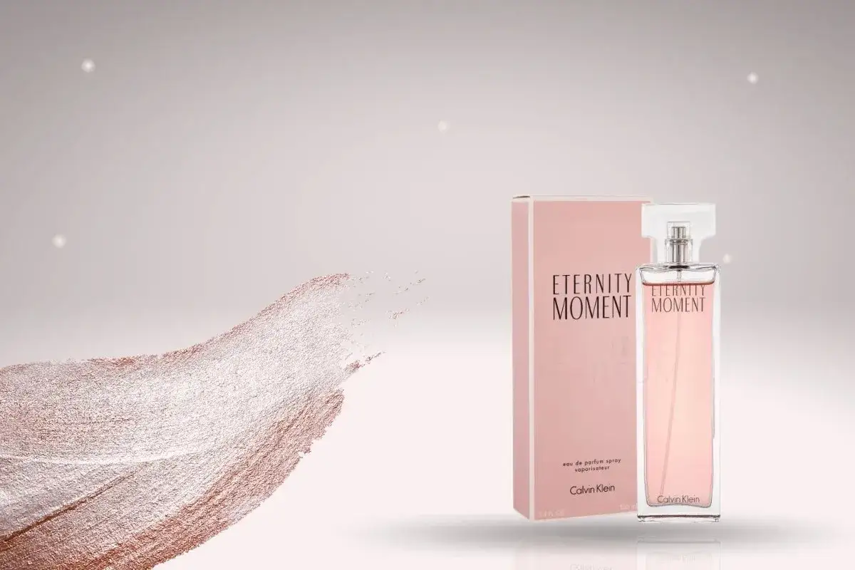 Perfumy Calvin Klein damskie, które najładniejsze? Eternity Moment w różowym flakonie i pudełku, obok subtelnego muśnięcia brokatu.